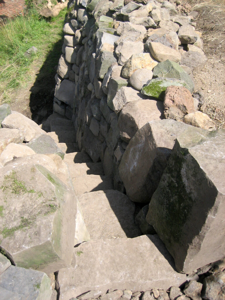 Vue plongeante sur un escalier et des murets en pierre sèche à Saint-Arcons-d’Allier
