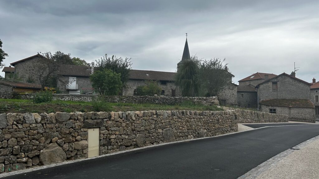 Long parement en granite de réemploi devant les maisons et le clocher de Montregard