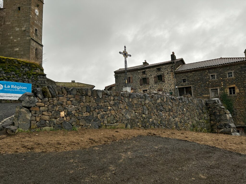 Pierre sèche et paysage de Pébrac Mur en basalte de récupération dans le bourg de Pébrac, devant les bâtiments en pierre