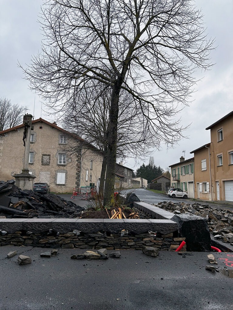Muret d’aménagement dans le bourg de Borne Muret en pierre sèche avec couvertines autour d’un espace planté à Borne