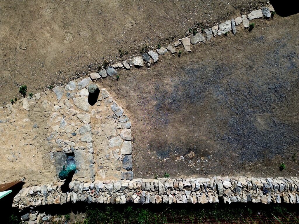 Vue aérienne de la calade et du point d’eau bordés d’un mur en pierre sèche à Saint-Vénérand