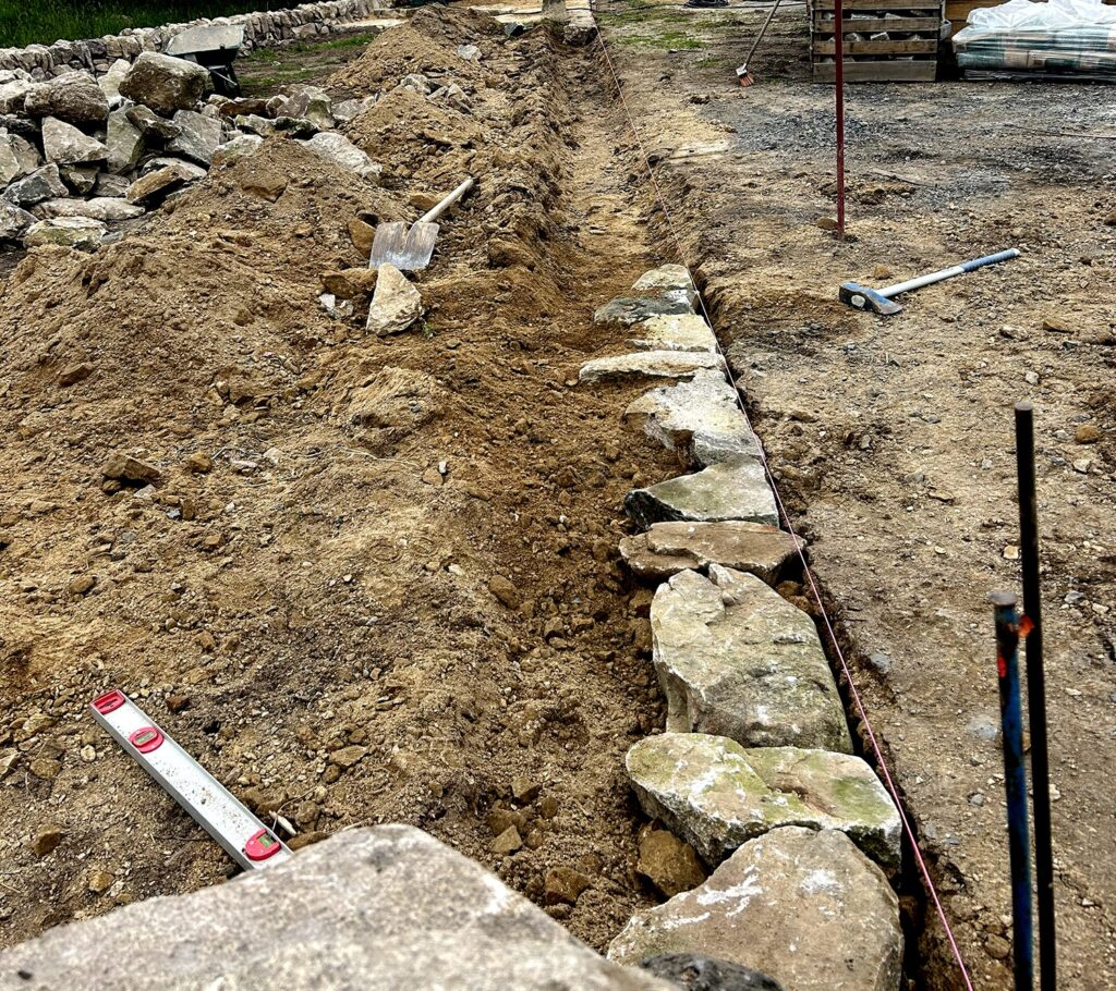 Première assise d’un mur en pierre sèche avec cordeau de tracé à Saint-Vénérand